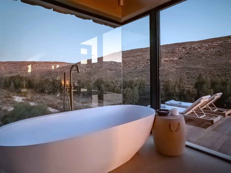 Floating bathtub overlooking mountains via floor to ceiling glass windows